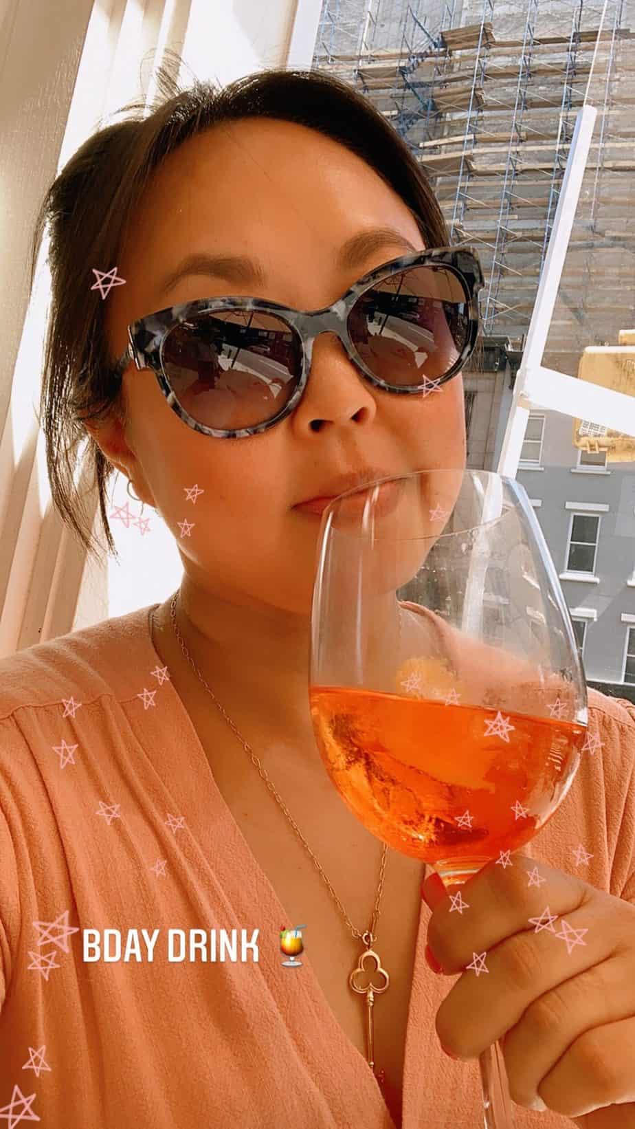 Girl in sunglasses holding an aperol spritz