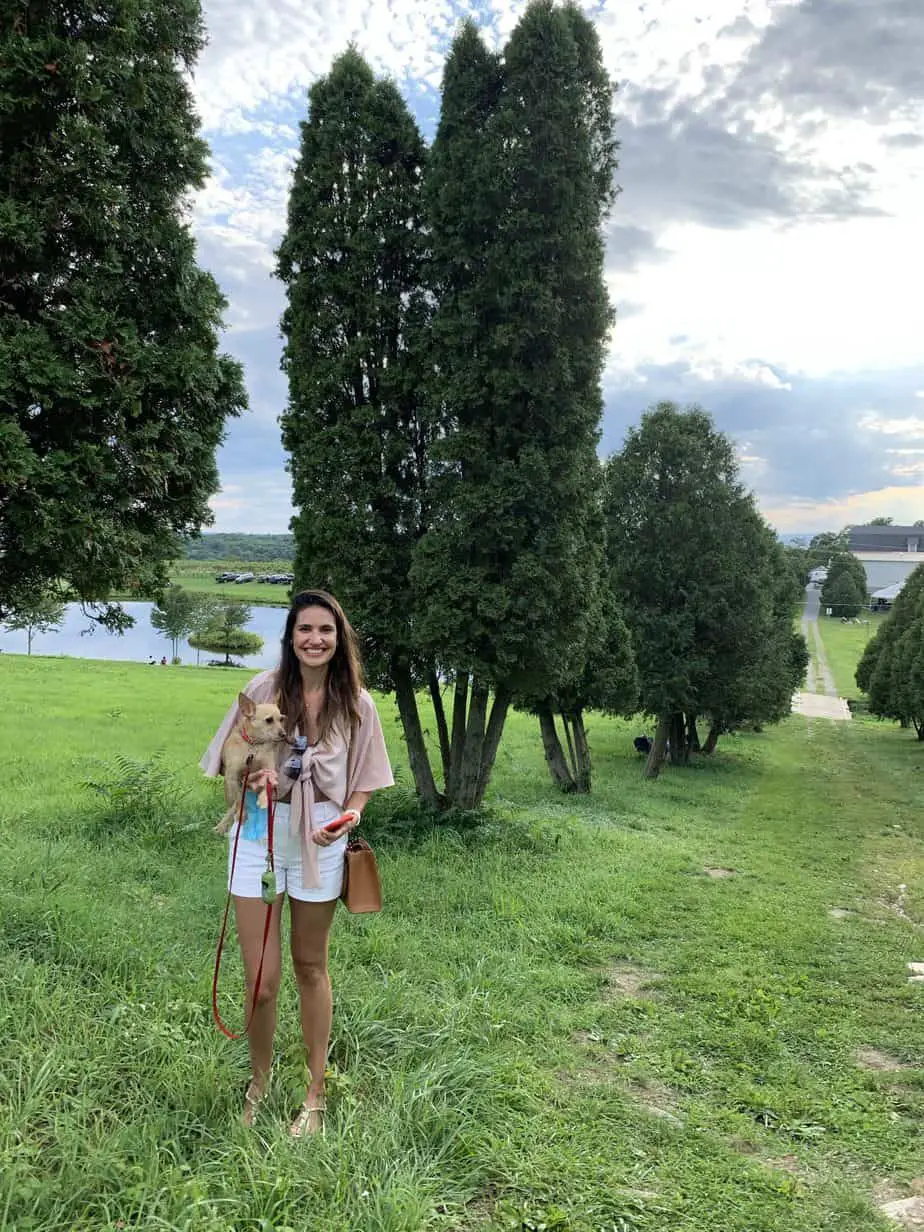 Girl holding a dog in front of trees