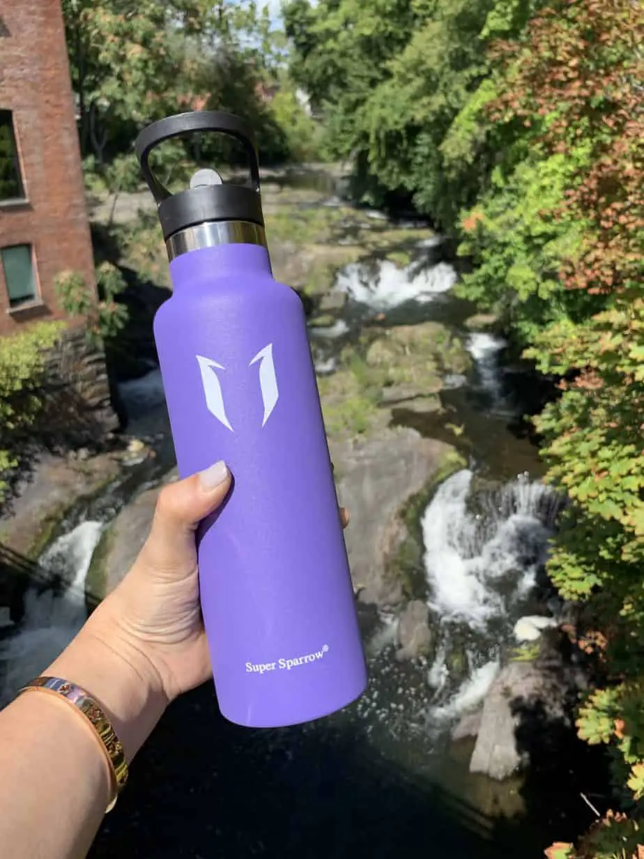 Super Sparrow water bottle in lavender against a backdrop of waterfalls