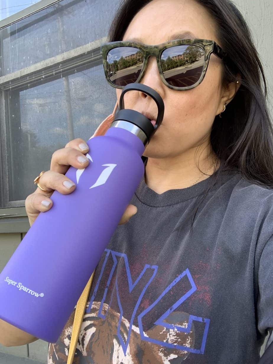 Girl in sunglasses drinking from a purple bottle